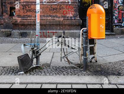 Reste von Vandalismus-Fahrrad mit Teilen gestohlen neben Mülltonne in der städtischen Straße, Mitte, Berlin Stockfoto