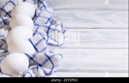 Viele frische rohe Hühnereier in einer Karton-Box, Hühnchen weiße Eko-Eier auf einem Stück Tuch, Flatlay, Copyspace Stockfoto