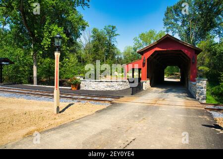 Eine restaurierte überdachte Brücke in der Nähe einer Eisenbahnstrecke Ein sonniger Tag Stockfoto