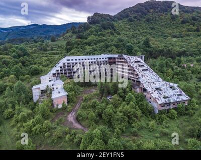 Luftdrohne Blick auf massive verlassene Hotel in Wald Berge Stockfoto