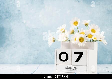White Cube Kalender für märz mit Gänseblümchen über geschmückt Blauer Hintergrund mit Kopierbereich Stockfoto