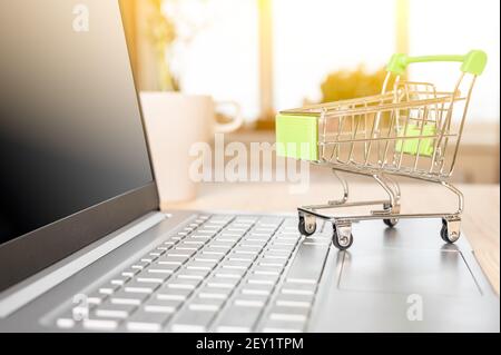 Online-Shopping- und Lieferkonzept. Kleiner Einkaufswagen auf Laptop-Tastatur. Einkaufswagen mit Laptop-Computer, die Web-Shop für Stockfoto