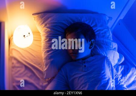 Sechs Jahre alt bouy schlafen mit LED-Nachtlampe, Schulkind träumen. Kind wütend auf Dunkelheit. Stockfoto