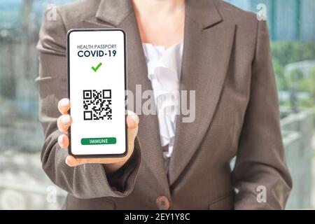 Covid-19 Health Pass App Konzept auf Smartphone. Frau Hodling Telefon. Frau hält Smartphone mit einem QR-Code digitale Illustration von Covid-19 Gesundheit Stockfoto