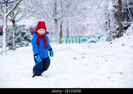 Schöne Kleinkind Kind, niedlichen Jungen, spielen in verschneiten Park Winterzeit, bewölkten Tag Stockfoto