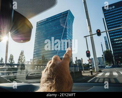 The Hague, Niederlande - 21. Aug 2018: POV männliche Hand zeigt vom Autofenster auf die hohen Wolkenkratzer mit Deloitte Audit Big Four Headquarter in der niederländischen Hauptstadt - Besuch in Den Haag Stockfoto