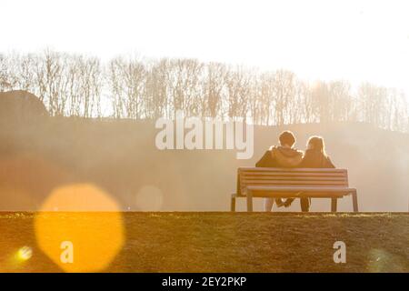 Schönes Paar sitzen auf der Bank im Park von schön beleuchtet Sonnenuntergang Stockfoto