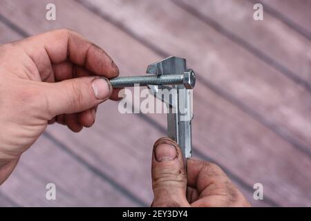 Messschieber und Schraube Rauh verschmierte Arbeiterhände. Stockfoto