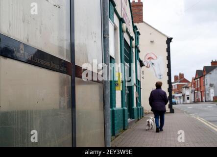 Ibstock, Leicestershire, Großbritannien. 5th. März 2021. Eine Frau geht mit einem Hund an einer Bushaltestelle vorbei. North West Leicestershire hat die höchste Coronavirus-Rate in England nach den neuesten Public Health England Zahlen. Credit Darren Staples/Alamy Live News. Stockfoto