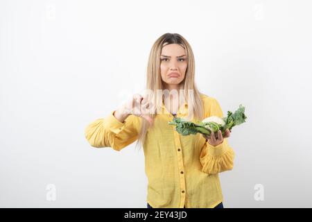 Bild einer hübschen Frau Modell mit Blumenkohl zeigt eine Daumen nach unten Stockfoto