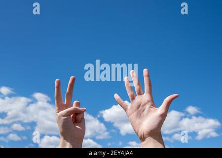 Nahaufnahme der weiblichen Hände mit sieben Fingern auf blauem Himmel. Nummer sieben in Gebärdensprache. Speicherplatz kopieren. Stockfoto