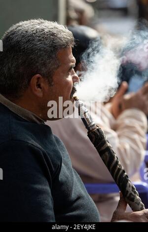 Profilportrait eines ägyptischen Mannes, der Rauch aus einer Shisha-Pfeife im Islamischen Viertel von Kairo ausatmet Stockfoto