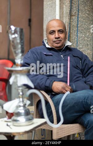 Porträt eines ägyptischen Mannes, der in einem Café (ahwa) in der Innenstadt von Kairo, Ägypten, eine Shisha-Pfeife raucht Stockfoto