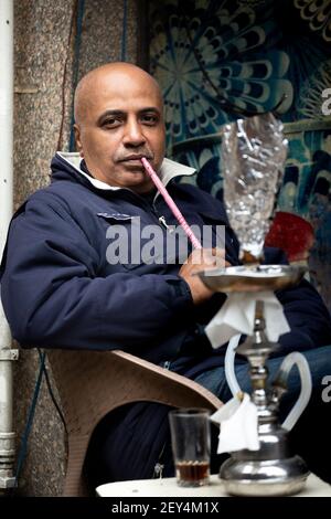 Porträt eines ägyptischen Mannes, der in einem Café (ahwa) in der Innenstadt von Kairo, Ägypten, eine Shisha-Pfeife raucht Stockfoto