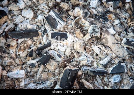 Rot-heiße Stücke von Kohle und Flamme in einer Bratpfanne zum Kochen. Abstrakter Hintergrund von brennenden Kohlen. Textur. Stockfoto