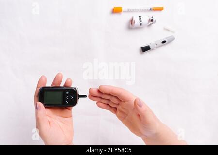 Zugeschnittenes Foto. Healthcare und medizinisches Konzept, die diabetischen Hände messen den Gehalt an Glukose im Blut. Weltdiabetestag, 14. November. Stockfoto