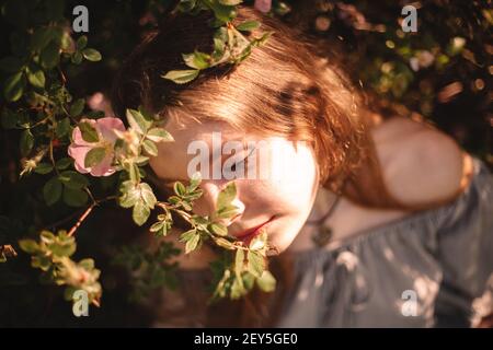 Friedliche junge Frau, die im Sommer inmitten von Blumen im Park sitzt Stockfoto