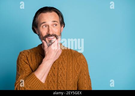 Foto-Porträt von mittleren Alters bärtigen Mann nachdenklich suchen leeren Raum In braunem Strickpullover isoliert auf lebhaft blauem Hintergrund Stockfoto