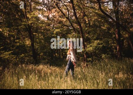 Teenager-Mädchen zu Fuß durch grünes Gras im Wald im Sommer Stockfoto