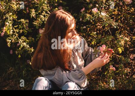 Teenager-Mädchen hält Blume im Sommer Park während der Sonne sitzen Tag Stockfoto