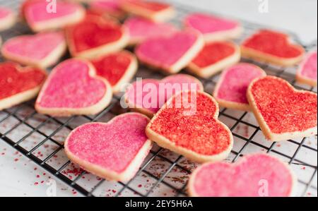 Nahaufnahme von vielen dekorierten herzförmigen Plätzchen auf Kühlregal. Stockfoto