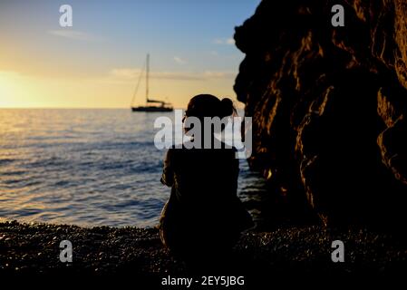 Silhouette einer besinnlichen jungen Frau, die einen schönen Sonnenuntergang genießt Stockfoto