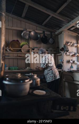 Ältere Frau in einer alten Küche, die Mais-Tortillas macht Stockfoto