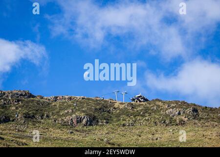 Der Mond tagsüber über der Christchurch Gondola, Neuseelandmit blauem Himmel und einem grünen Berg Stockfoto