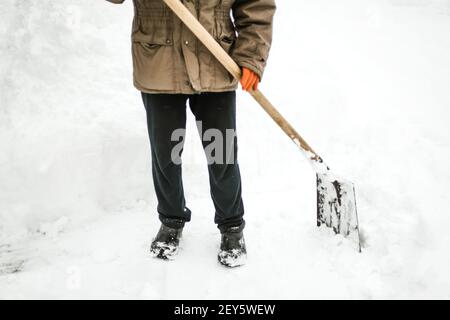 Der Mensch entfernt nach einem Schneesturm Schnee von seinem Hof und schaufelt Schnee Stockfoto