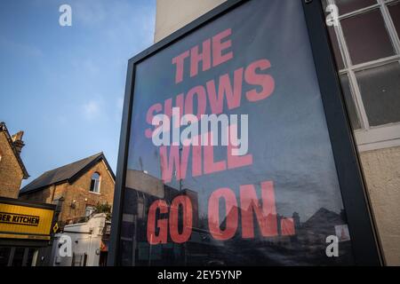 Das umrahmte Poster „The Shows will Go On“ hing an der Außenseite des Wimbledon Theatre, während die Londoner Theater während der Coronavirus-Sperre geschlossen bleiben Stockfoto