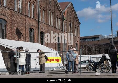 Dortmund, NRW, 05th. März 2021. Außerhalb des Zentrums hat sich eine geordnete Schlange von Personen mit Terminen gebildet. Beschilderung und Wegbeschreibung zum Impfzentrum Phoenix-West. Phoenix West, ein ehemaliges Hochofen- und Industriegelände, das heute Kultur- und Musikstätten beherbergt, ist derzeit Dortmunds größtes und am meisten frequentierte Impfzentrum. Die Impfkampagne in Deutschland nimmt Fahrt auf. Anfang dieser Woche hat das deutsche Gesundheitsministerium und die impfkommission STIKO den Impfstoff von Astra Zeneca für die Verwendung in der Altersgruppe über 65 freigegeben. Außerdem können Hausarztpraxen schon bald Impfungen verabreichen. A Stockfoto