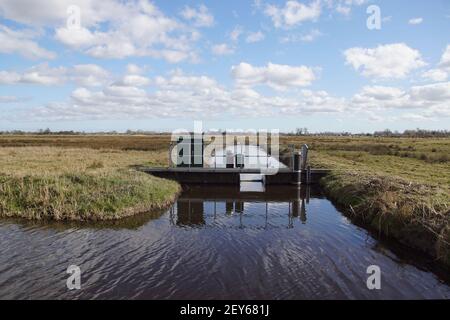 Sehr kleines holländisches Wehr (Holländisch: Klepstuw) in einem Graben. Das Wehr regelt die Wasserabflusskapazität des Oberflächenwasserkörpers. Spätswinter, Wiesen, Stockfoto