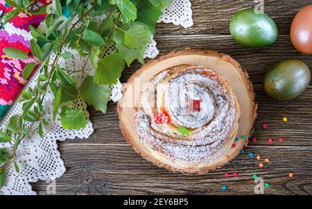 Süßer Osterkuchen, bemalte Eier, grüne Zweige auf einem Holztisch. Stockfoto