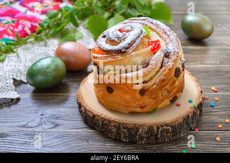 Osterkuchen, bemalte Eier, grüne Zweige auf einem Holztisch. Frühlingsferien Hintergrund Stockfoto
