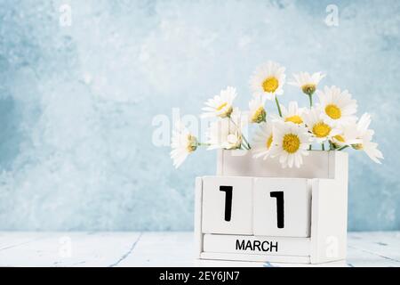 White Cube Kalender für märz mit Gänseblümchen über geschmückt Blauer Hintergrund mit Kopierbereich Stockfoto