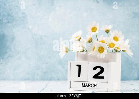 White Cube Kalender für märz mit Gänseblümchen über geschmückt Blauer Hintergrund mit Kopierbereich Stockfoto