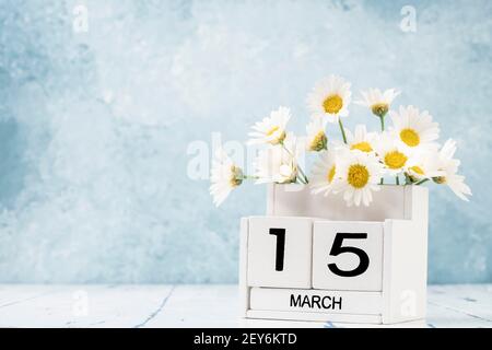 White Cube Kalender für märz mit Gänseblümchen über geschmückt Blauer Hintergrund mit Kopierbereich Stockfoto