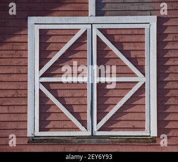 Weißes Quadrat geometrisch geformten Holzfensterrahmen auf alten roten Holzscheune Quadrat und Dreiecke Scheune Dekoration außerhalb Wand horizontalen Format Raum Stockfoto