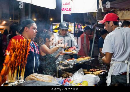 Mexikaner kaufen gegrilltes Fleisch am Imbissstand auf dem Nachtmarkt entlang der Malecón, Esplanade im Badeort Puerto Vallarta, Jalisco, Mexiko Stockfoto