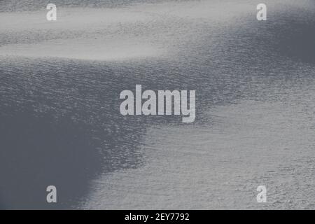 Nahaufnahme von Neuschnee im Sonnenlicht Schatten werfen strukturierten Wetterhintergrund oder Hintergrund horizontal Format weißen Raum für Typ Schneeflocken Kristalle Stockfoto