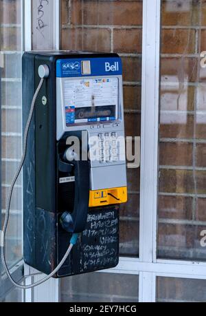 Ottawa, Ontario, Kanada - 6. Februar 2021: Ein abgenutztes Bell Canada Payphone mit Graffiti in einer schmutzigen Telefonzelle auf der Bank Street in Ottawa. Stockfoto