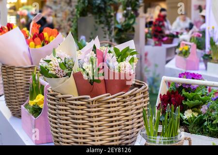 Verkauf von Blumen für die Frühlingsferien. Blumensträuße von Hyazinthen in Papier in einem Weidenkorb auf der Theke gewickelt. Blumengeschäft. Lifestyle-Blume Stockfoto
