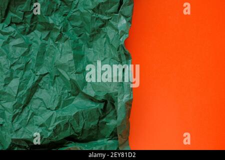 Leerer Papierhintergrund. Grün zerknittertes Papier auf einem orangen Hintergrund.Olive grün leeres Papier Hintergrund, Tapete, Platz für Text.Kreatives Papier Stockfoto