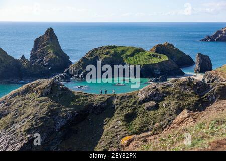 Erhöhte Aussicht auf Wanderer auf einem Bergrücken mit Blick auf Kynance Cove auf der Halbinsel Lizard in Cornwall, Großbritannien an einem sonnigen Tag Stockfoto