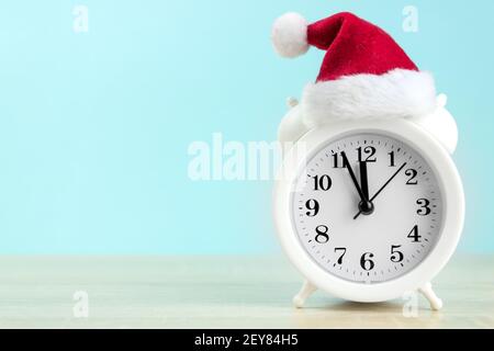 Weißer Wecker mit roter santa-Tasse auf Holztisch Mit blauem Hintergrund Stockfoto