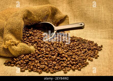 Horizontale Aufnahme einer offenen Tüte Kaffeebohnen auf der Seite. Die Bohnen werden mit einer Schaufel in die Bohnen aus dem Beutel gegossen. Dies ist ein überarbeitetes Bild Stockfoto