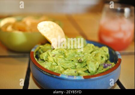 Köstliche frisch zubereitete, hausgemachte Guacamole mit Avocados, in Schüssel, mit Mehl Tortilla Chips und Rum Mojito Cocktail, Kalifornien, USA Stockfoto