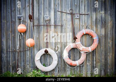 Rettungsring an der Wand der hölzernen Fischerhütte mit Seil. Orangefarbene Bojen Stockfoto