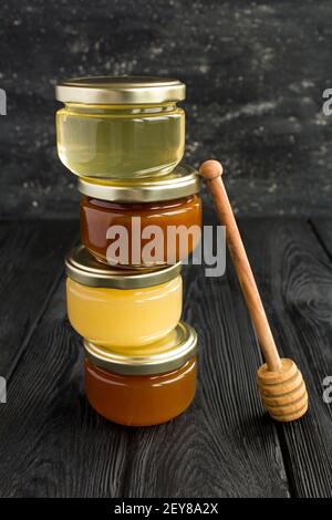 Verschiedene Honigsorten in kleinen Gläsern auf schwarzem Hintergrund. Position vertikal. Nahaufnahme. Stockfoto