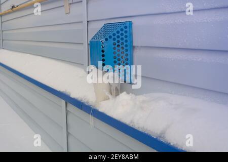 Koaxialkamin für Gaskessel an der Fassade des Hauses im Winter. Angesammelter Schnee und Eiszapfen auf der Motorhaube im Frost. Selektiver Fokus. Stockfoto